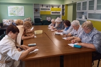 Senioru grupa sēž pie galda un pilda uzdevumu