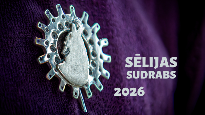 Sudraba rotaslieta uz tumši violeta auduma fona ar uzrakstu „Sēlijas sudrabs 2026”
