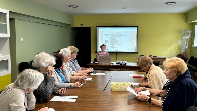 Seniori pie galda klausās prezentāciju