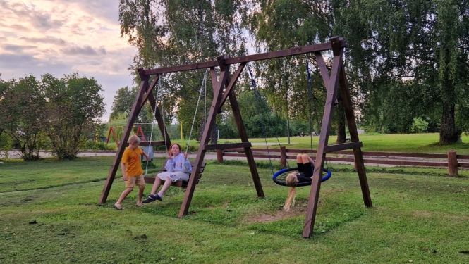 Bērni šūpojas koka šūpolēs