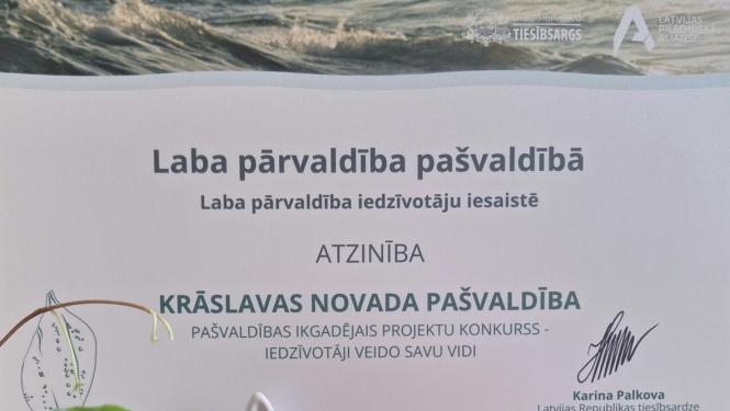Tiesībsarga atzinības diploms uz galda kopā ar augiem un dzīvnieku figūriņām