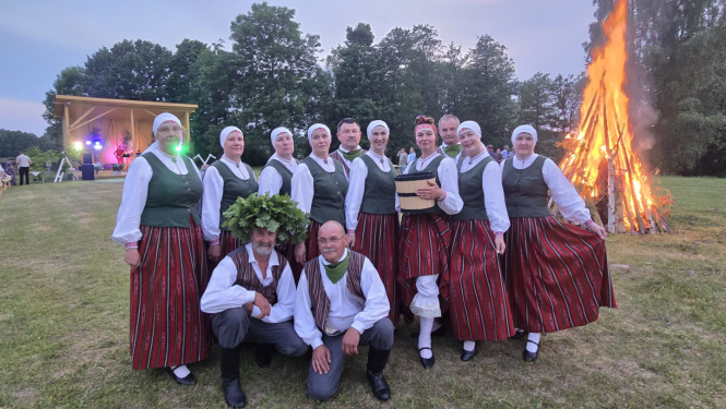 Dalībnieki tautastērpos pozē pie Jāņu ugunskura