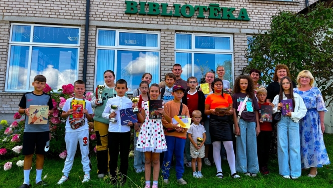 Bērni un pieaugušie pie bibliotēkas