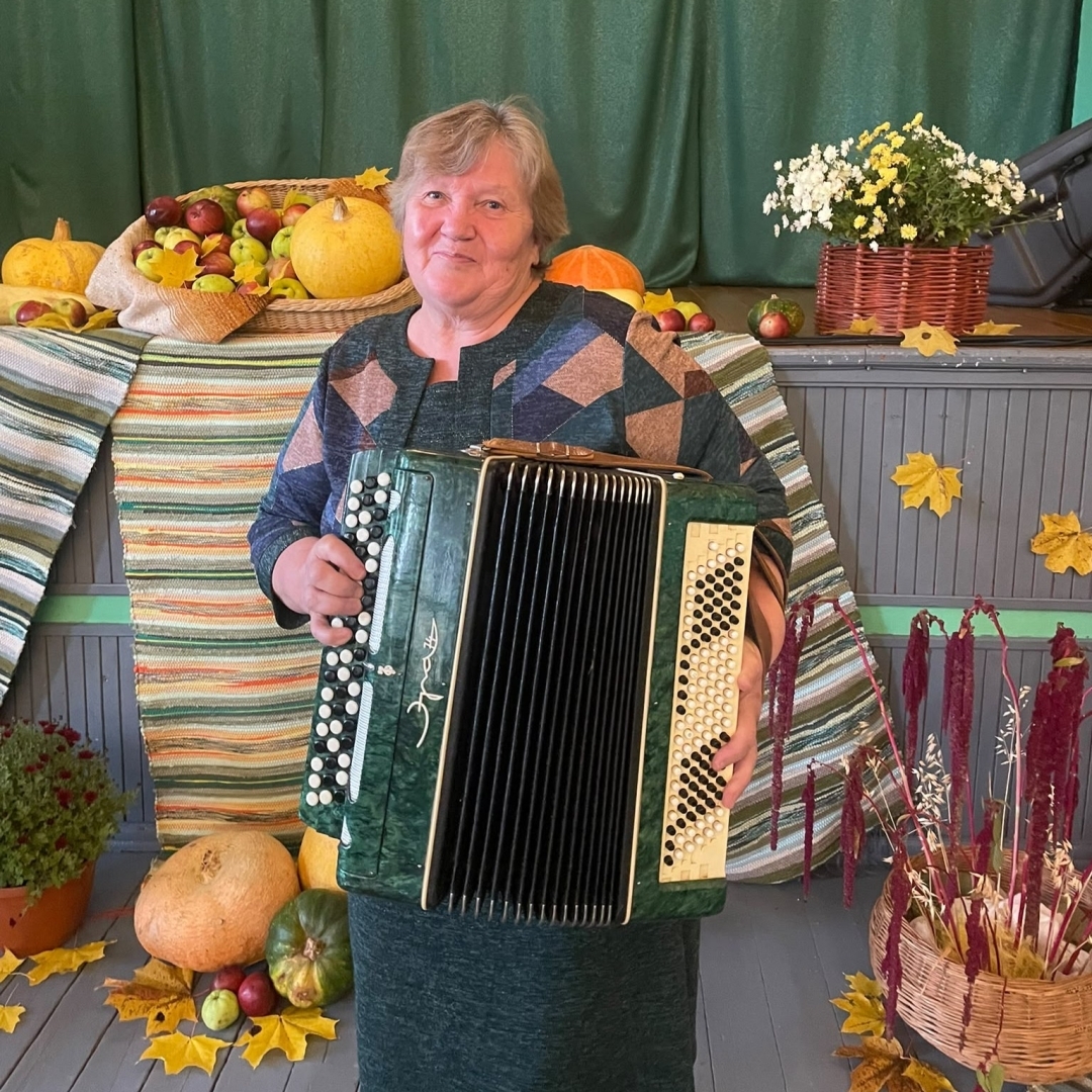 Sieviete ar akordeonu rudens dekorāciju fonā