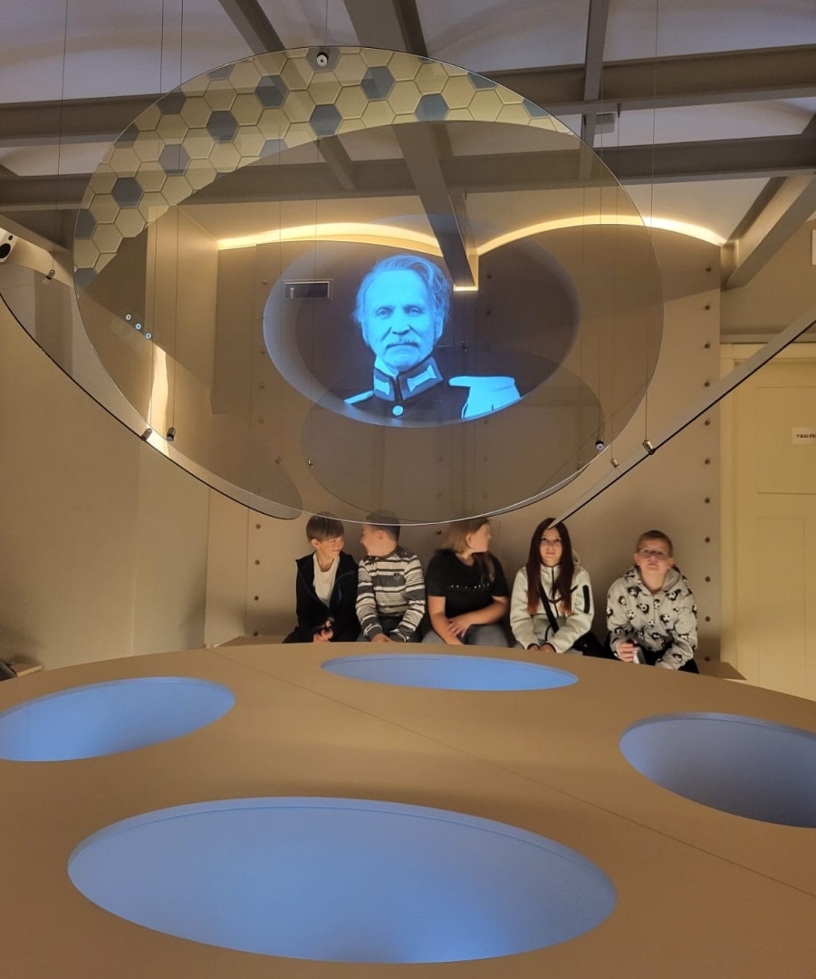 Skolēni vēro vēsturiska personāža video projekciju