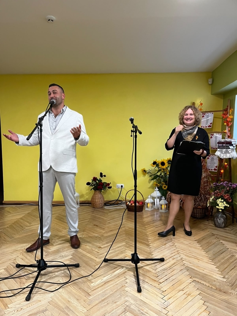Dziedātājs un pasākuma vadītāja uzstājas bibliotēkā