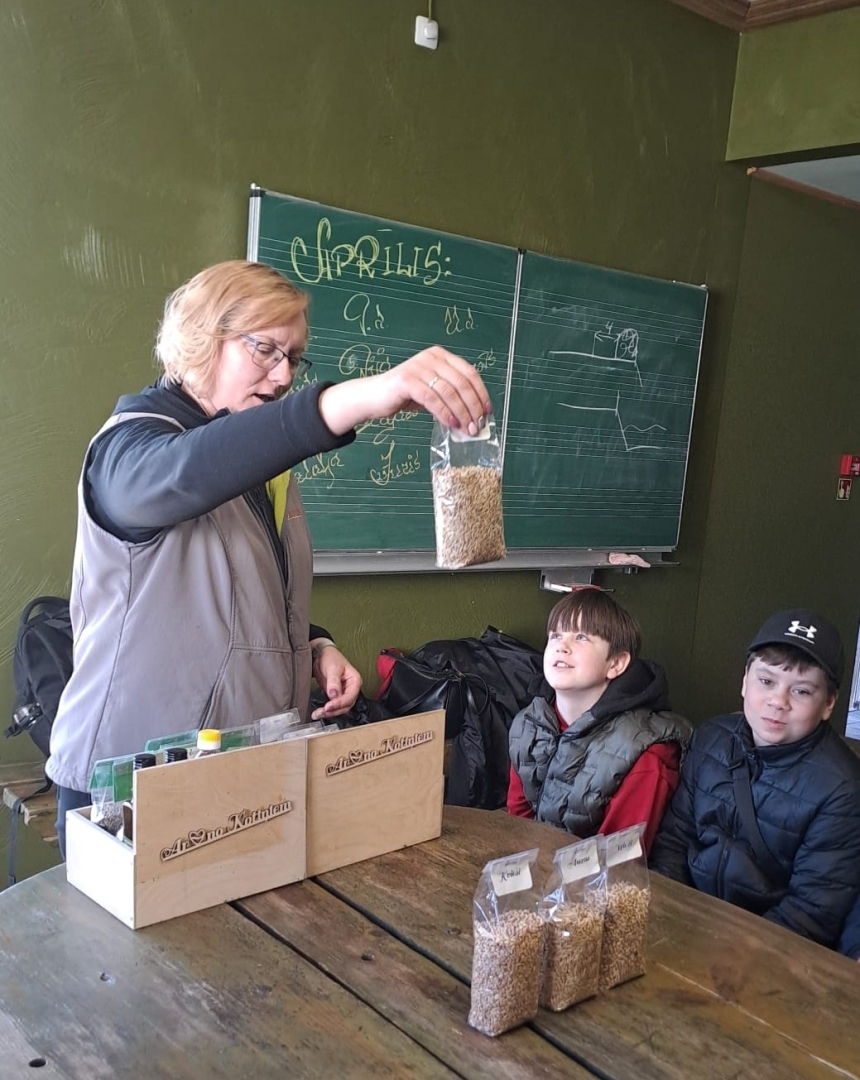 Skolotāja rāda skolēniem graudu paraugus