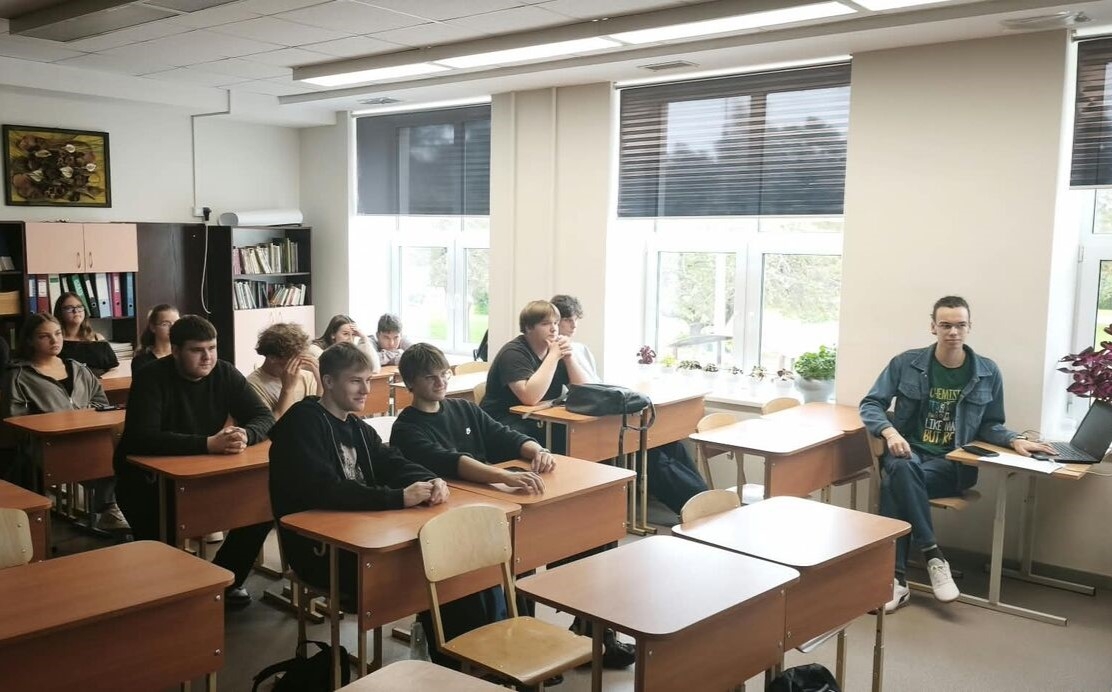 Skolēni klausās prezentāciju klasē.