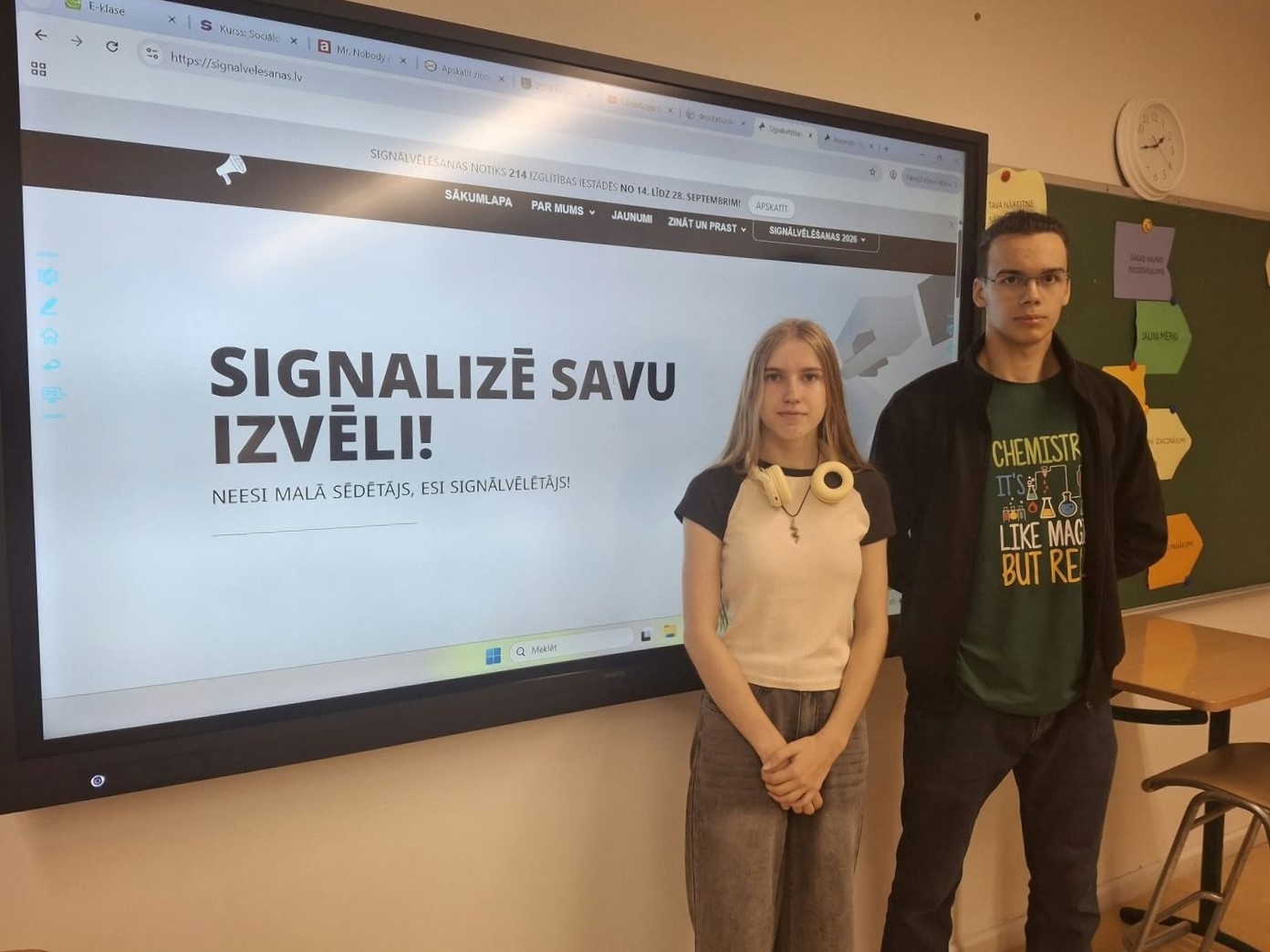 Divi jaunieši stāv pie ekrāna