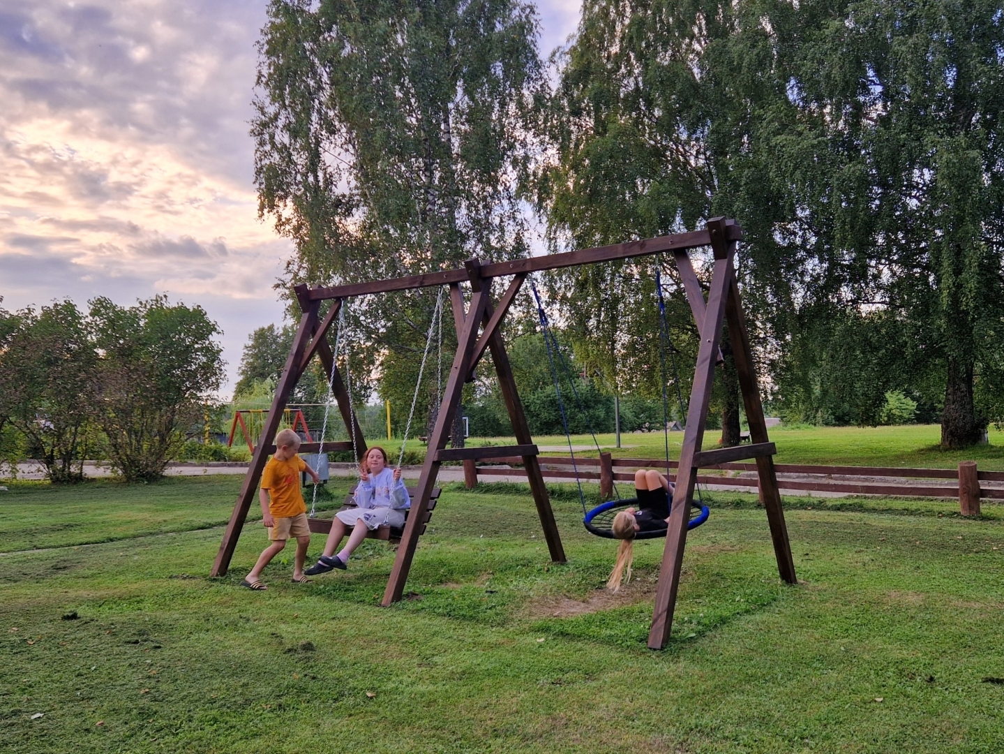 Bērni šūpojas koka šūpolēs