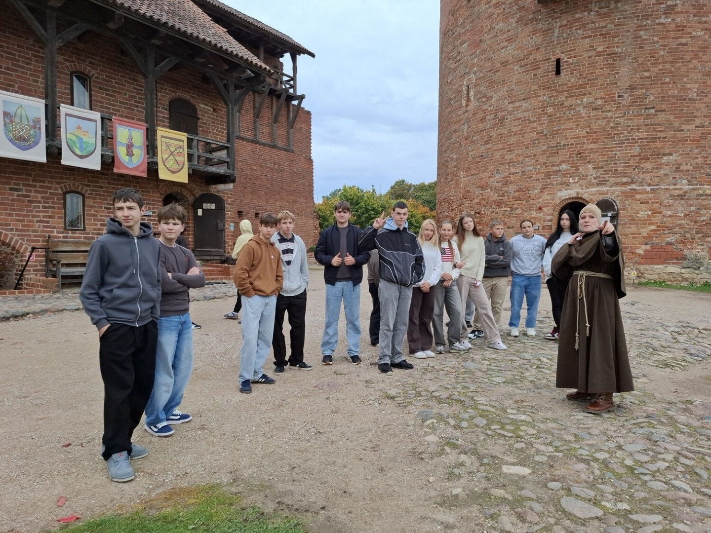 Skolēnu grupa kopā ar gidi viduslaiku pils pagalmā