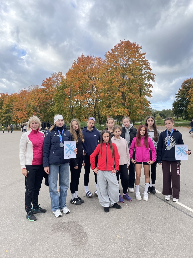 Rollerslēpotājas ar treneri rudens krāsās iekrāsotā parkā