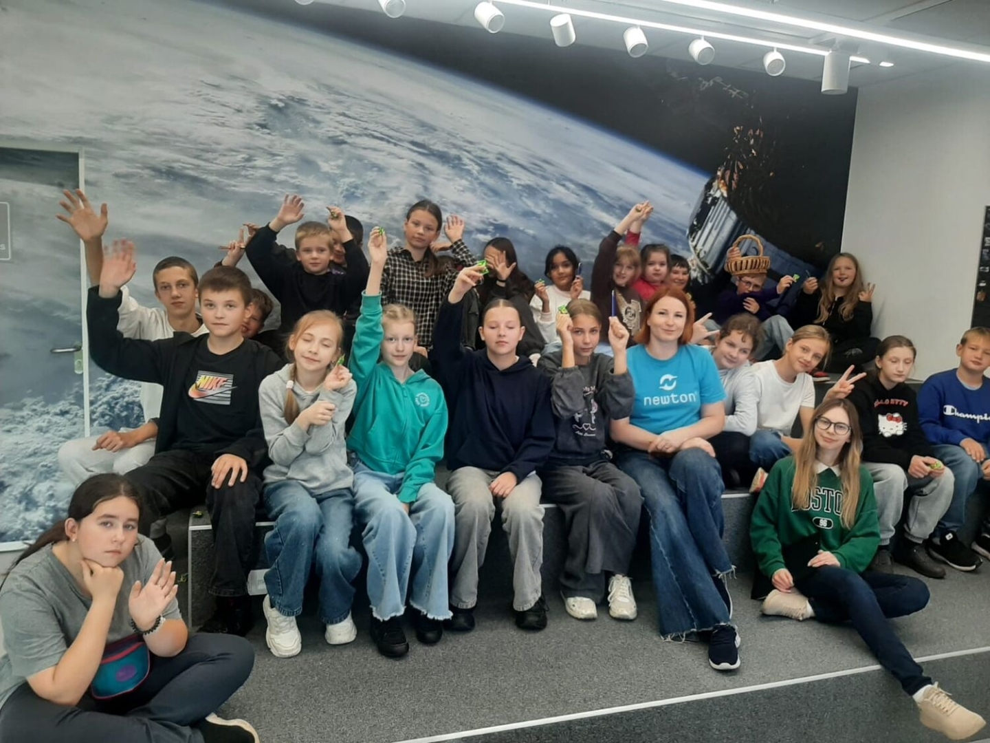 Skolēnu grupa pie sienas ar kosmosa attēlu