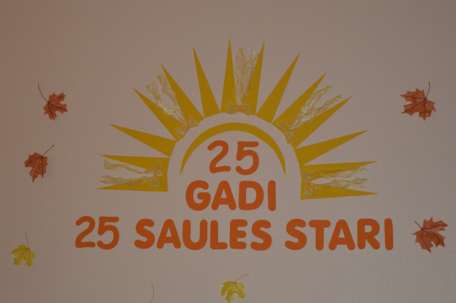 ienas noformējums ar uzrakstu „25 gadi. 25 Saules stari.”