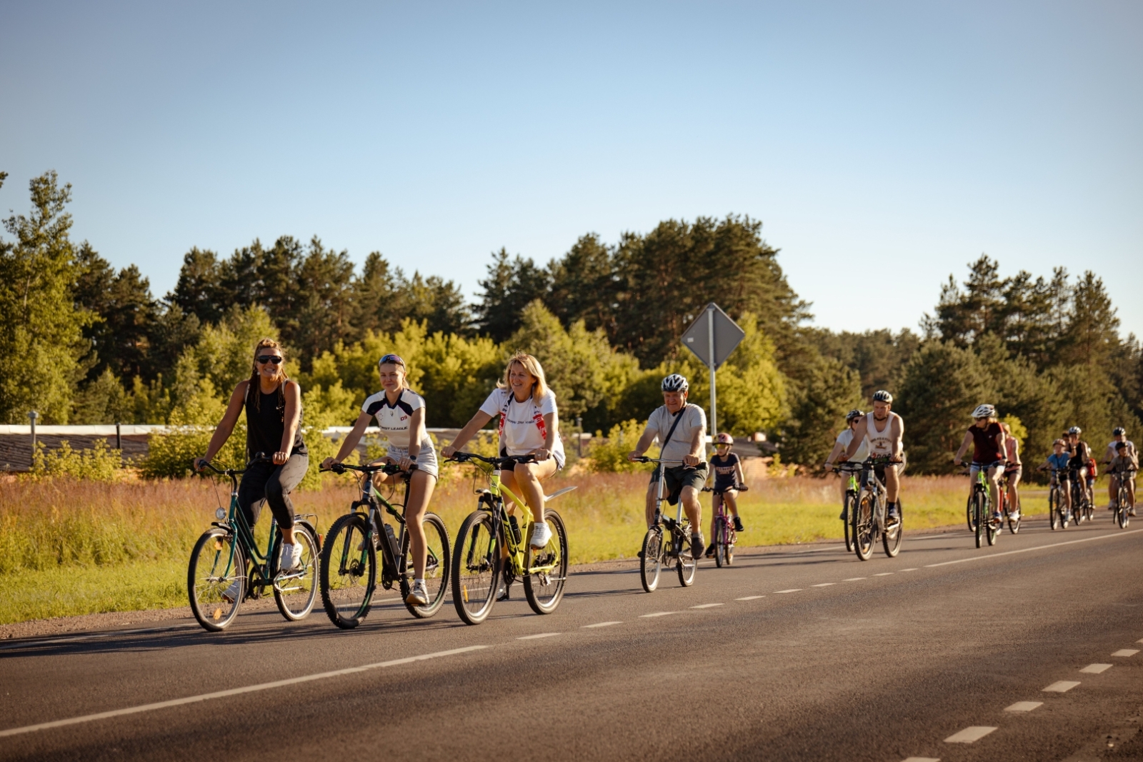 Velobraucēju grupa dodas kopīgā braucienā gar mežmalu
