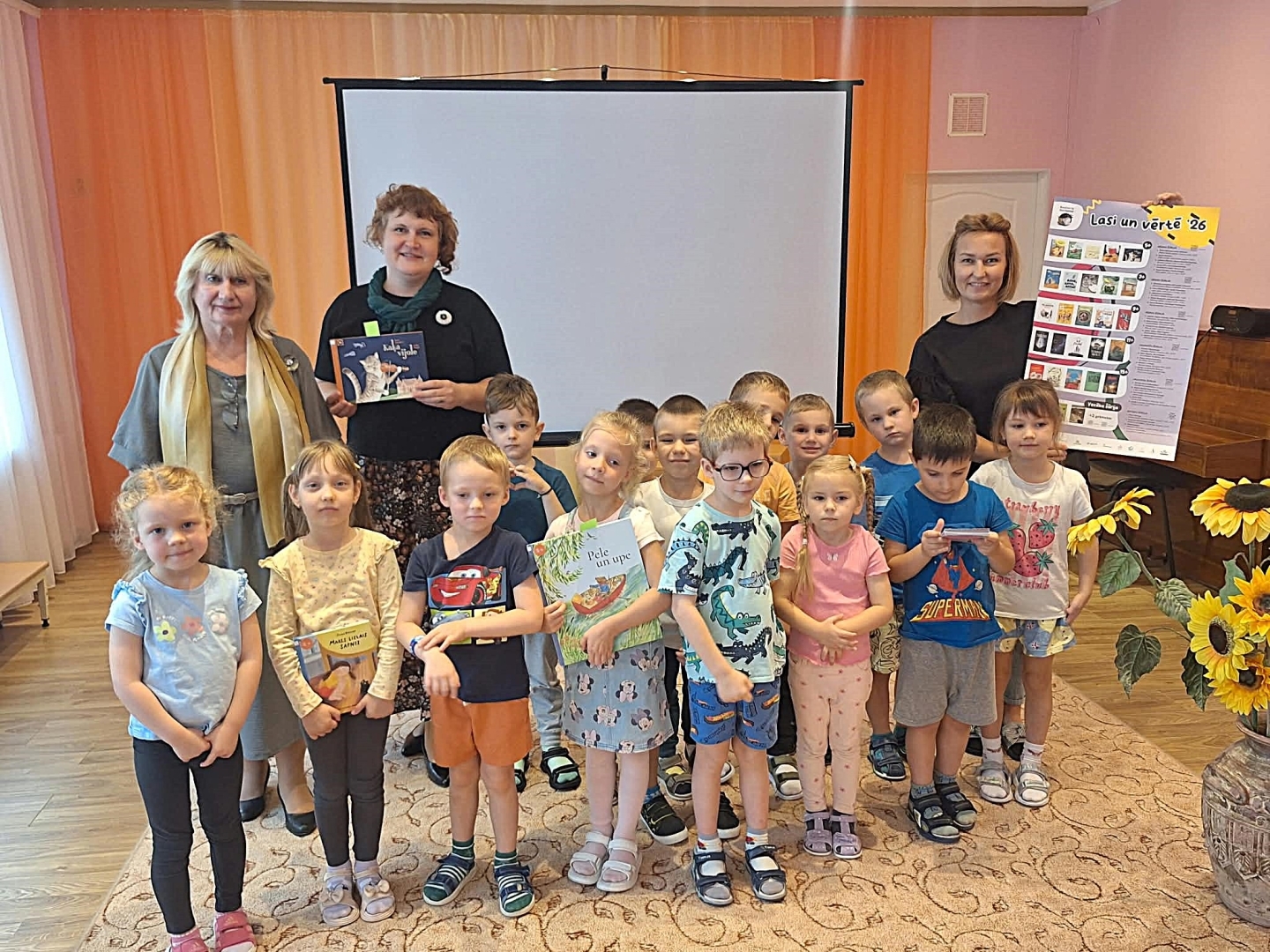 Bērnu grupa ar skolotājām un grāmatām