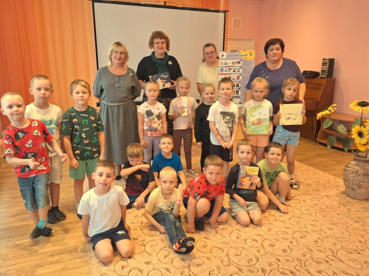 Bērnu grupa ar skolotājām un grāmatām