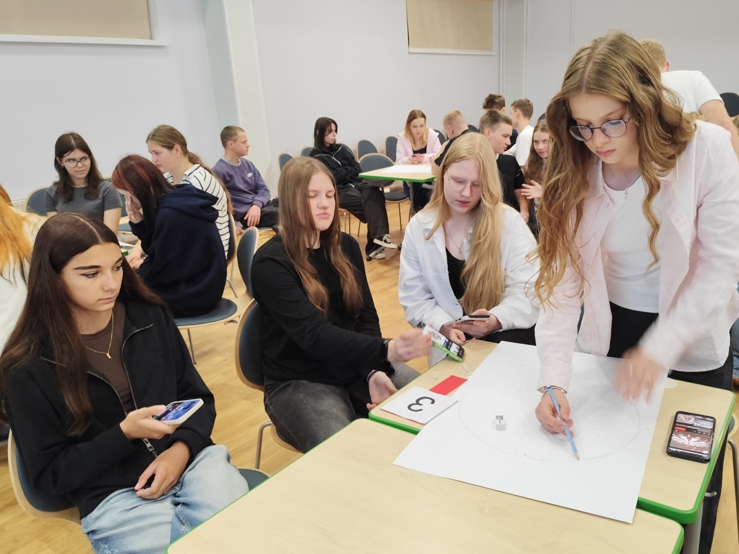 Jaunieši grupā veido zīmējumu un strādā pie kopīga uzdevuma