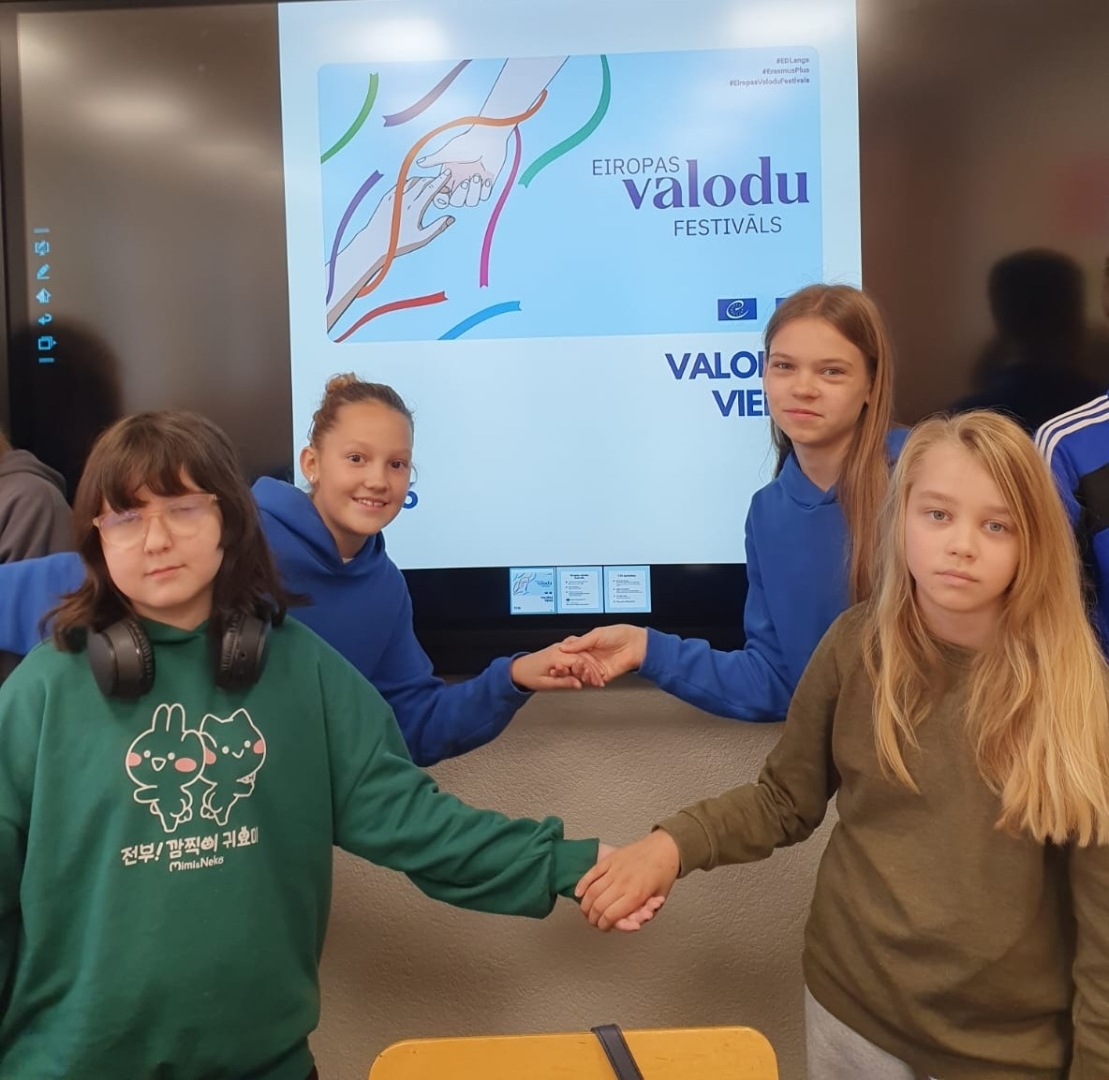 Četras skolnieces pie interaktīvās tāfeles demonstrē Eiropas Valodu festivāla materiālu