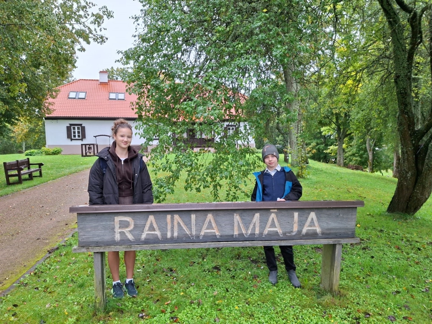 Divi skolēni pie „Raiņa mājas” zīmes
