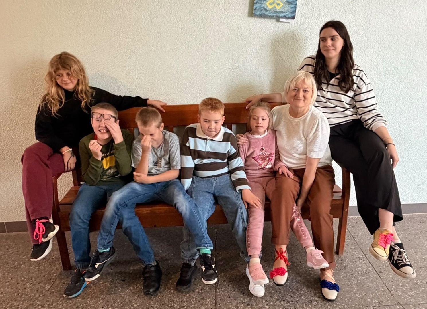Bērnu grupa un divas pieaugušas sievietes uz dīvāna