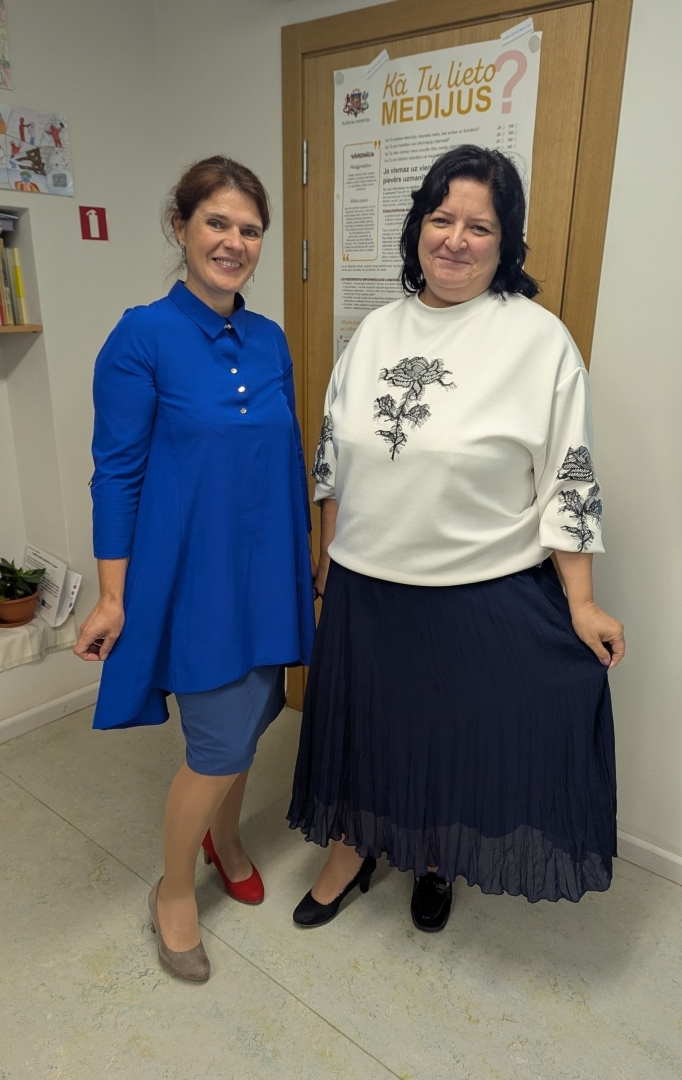 Divas skolotājas pozē skolas gaitenī