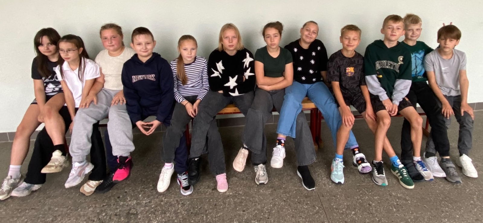 Skolēnu grupa sēž rindā uz sola