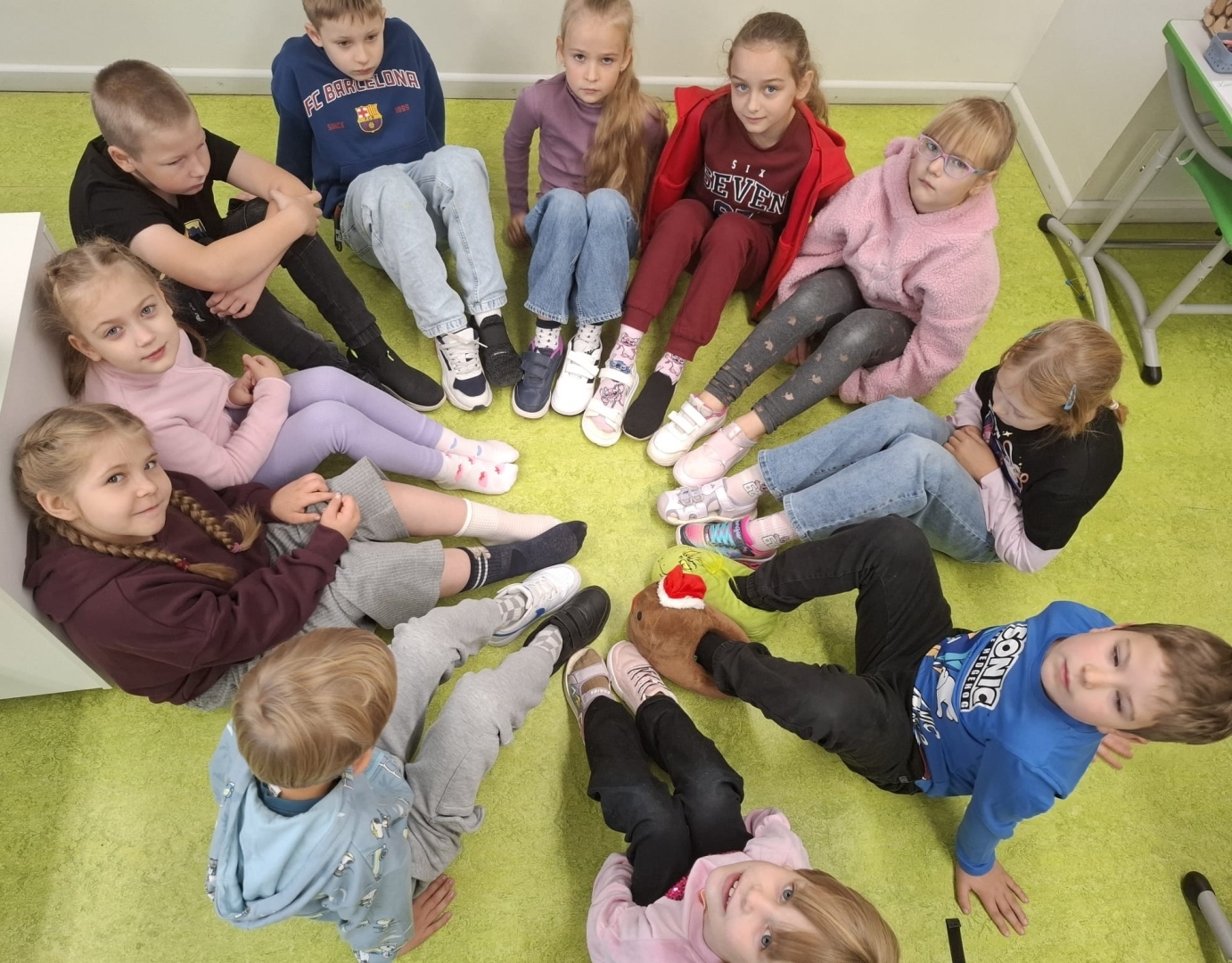 Bērni sēž aplī uz klases grīdas