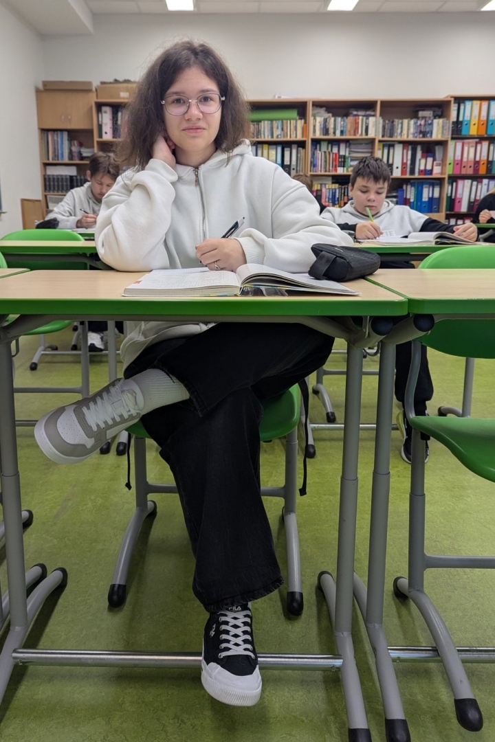 Skolniece sēž pie galda klasē