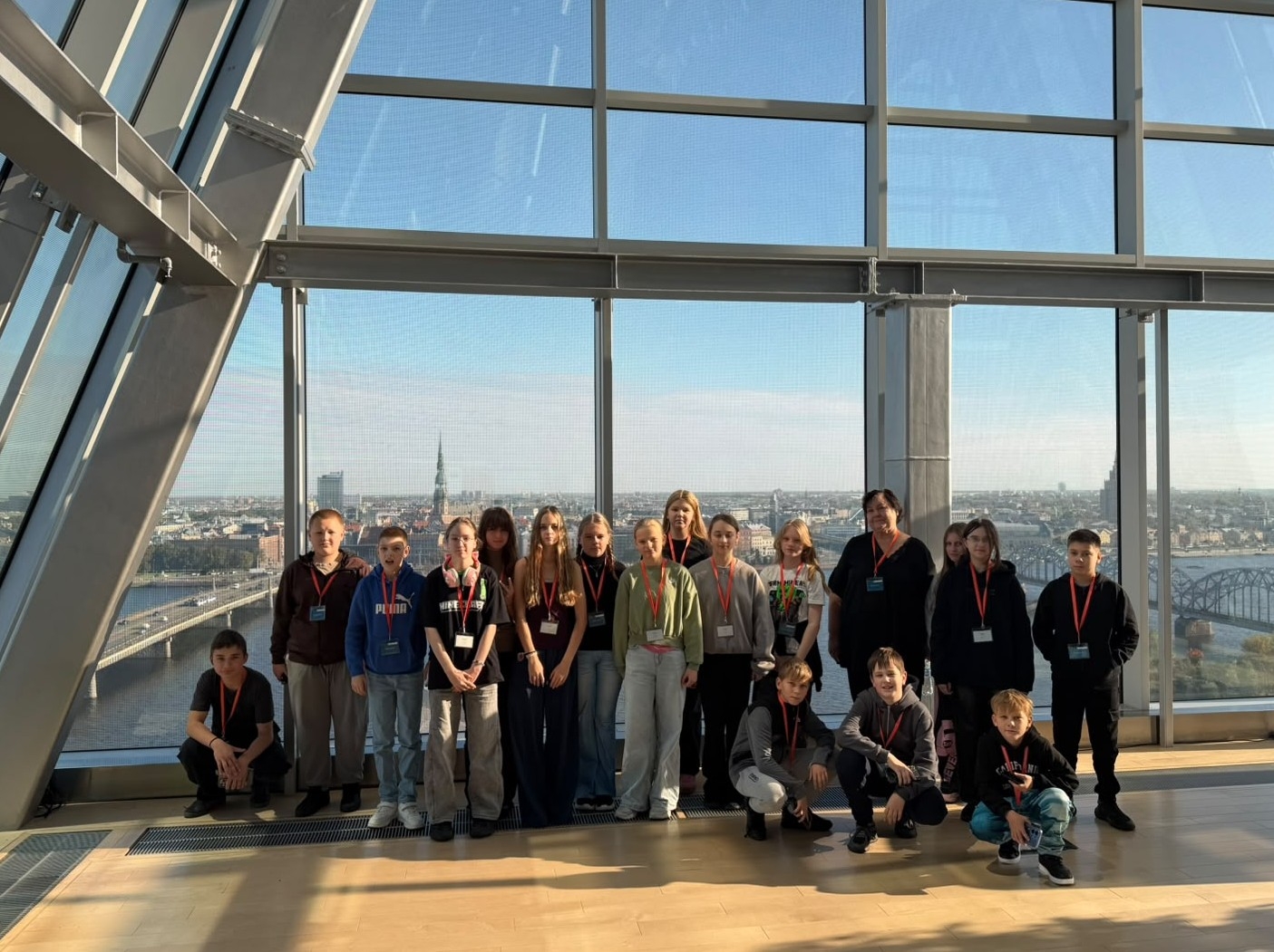 Skolēnu grupa uz Rīgas panorāmas fona