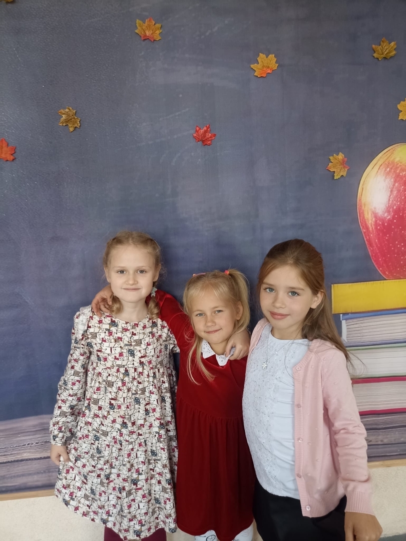 Trīs meitenes pozē pie rudens tematikas fona