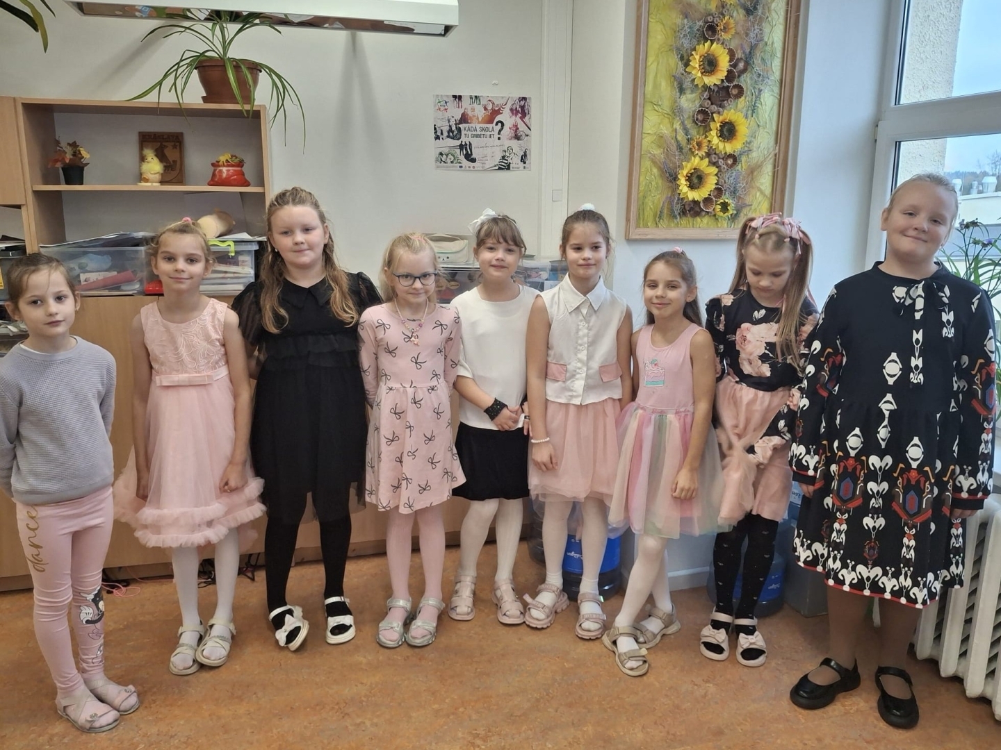 Skolnieces svinīgi pozē klases telpā
