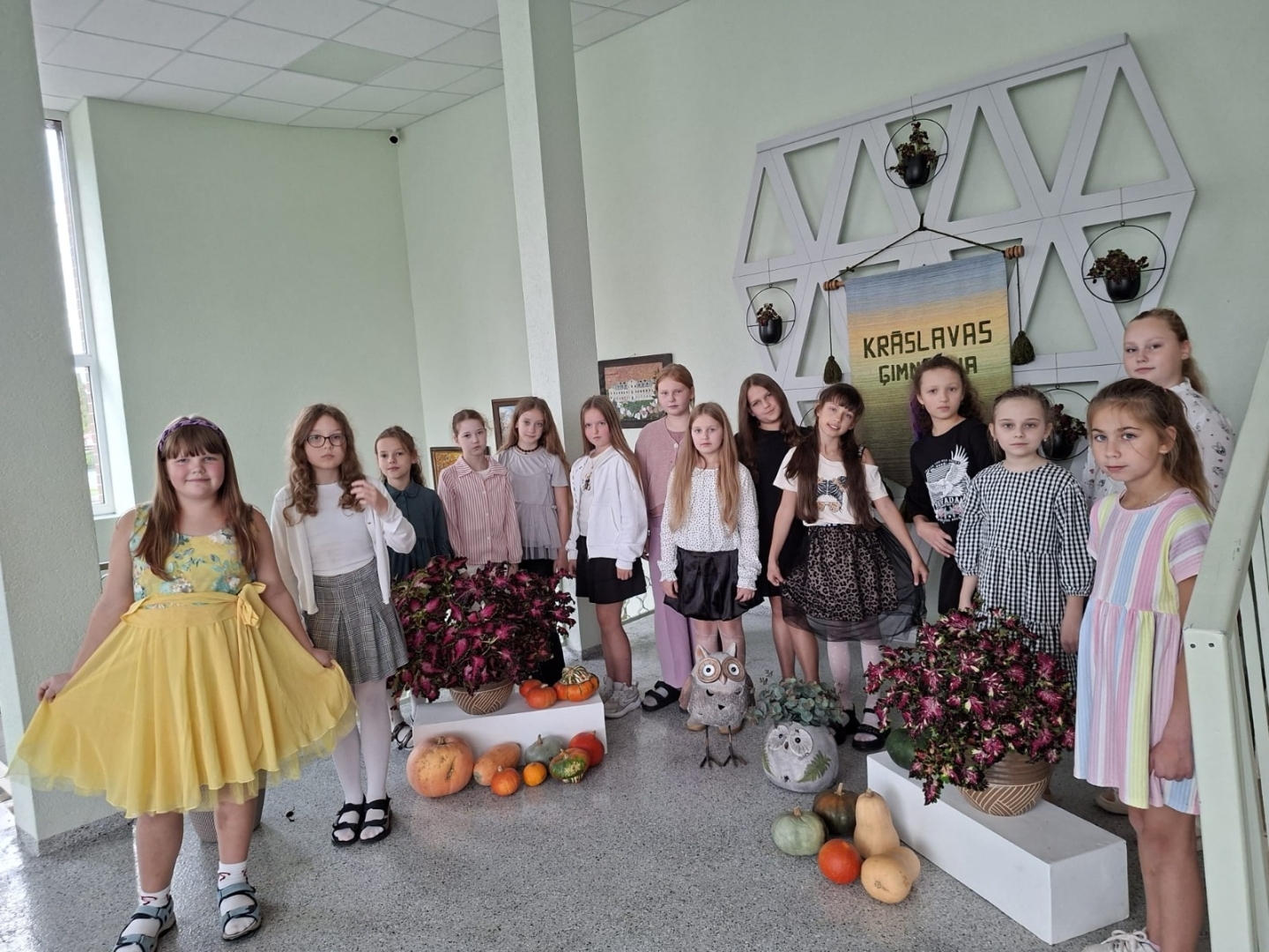 Skolnieču grupa pie rudens dekorācijām skolas gaitenī