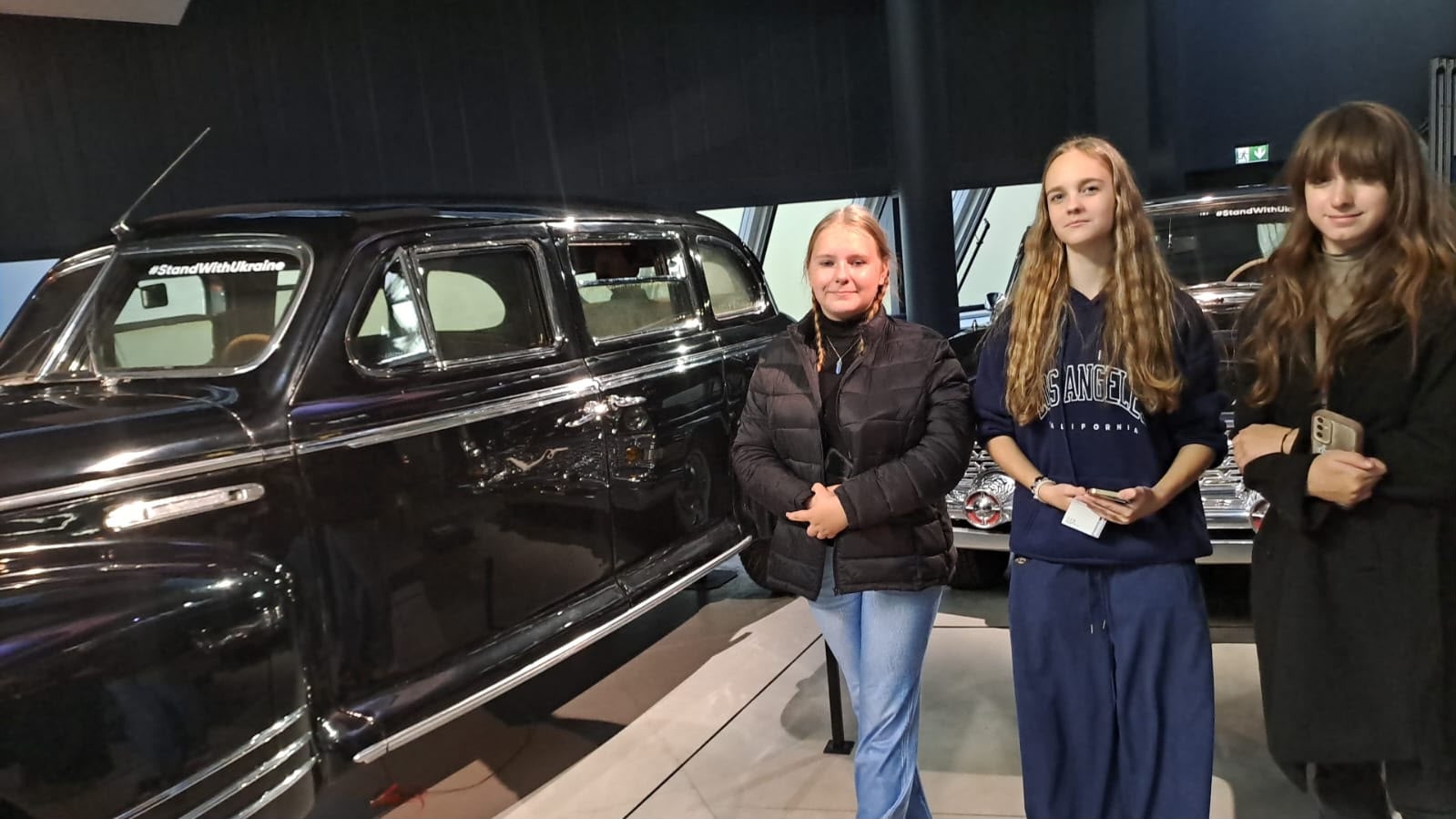 Skolēni pozē pie vēsturiskas automašīnas Rīgas Motormuzejā
