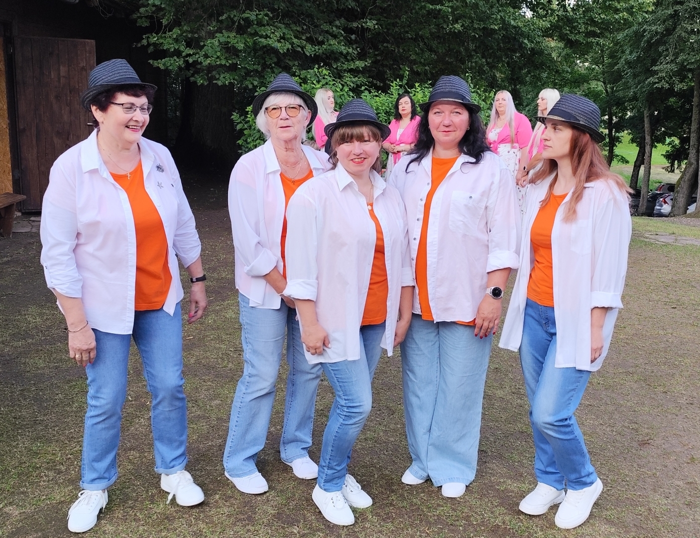 Sieviešu radošais kolektīvs baltos kreklos un oranžos t-kreklos