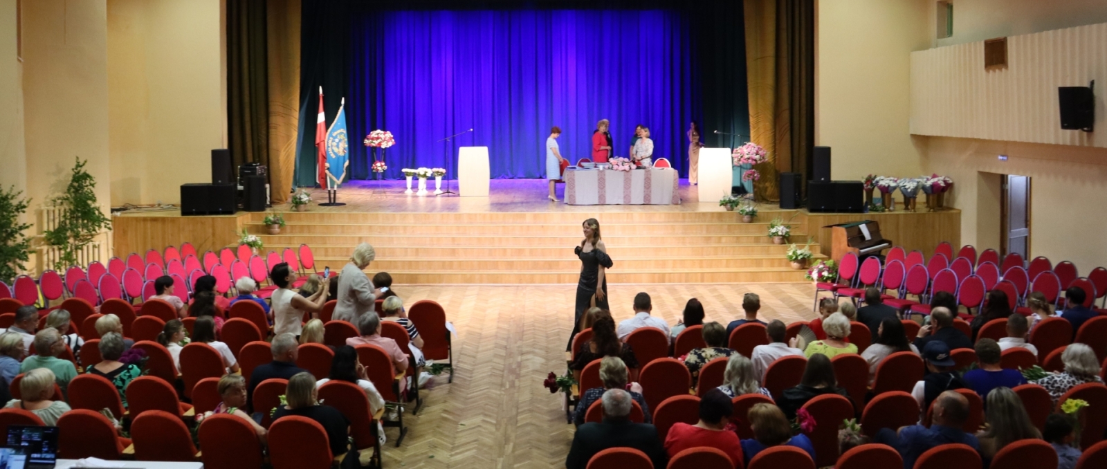 Izlaiduma ceremonija zālē ar skatītājiem un skatuvi