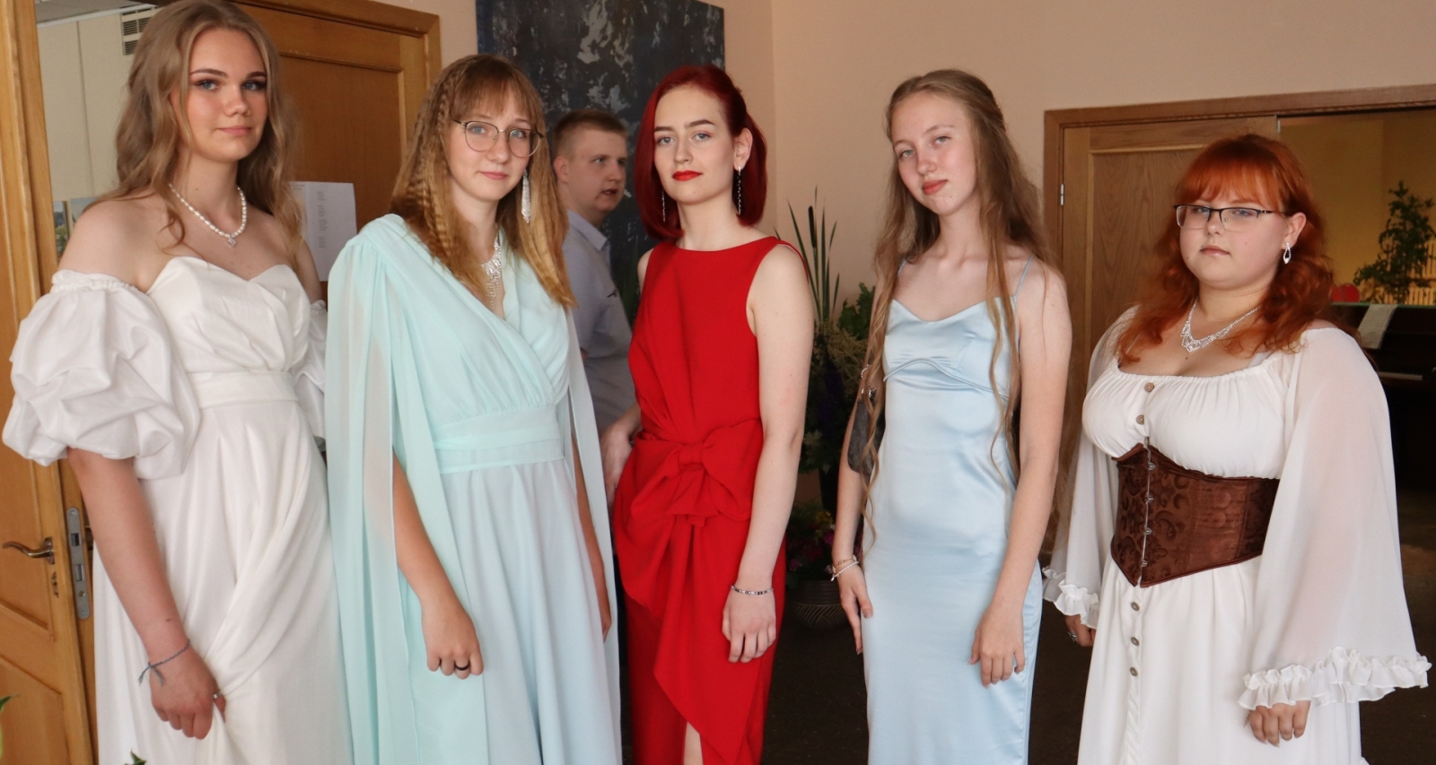 Piecas absolventes svinīgos tērpos pirms izlaiduma