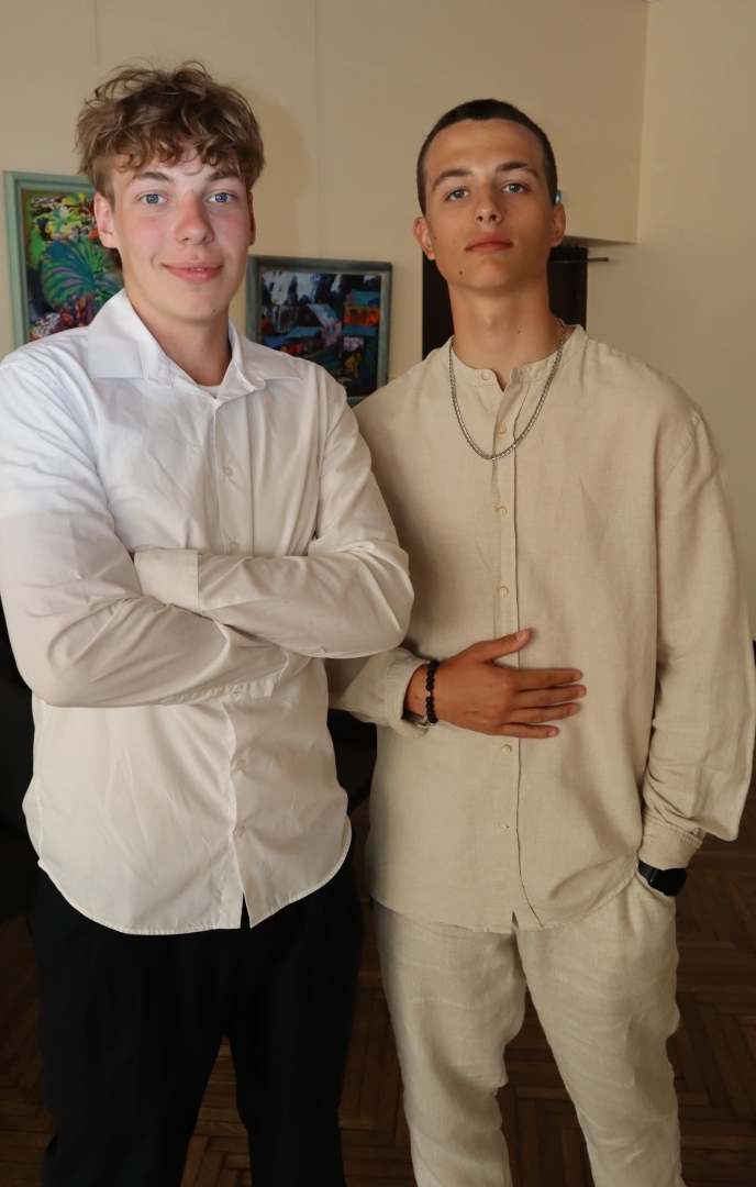 Divi jaunieši svinīgā apģērbā pozē kamerai