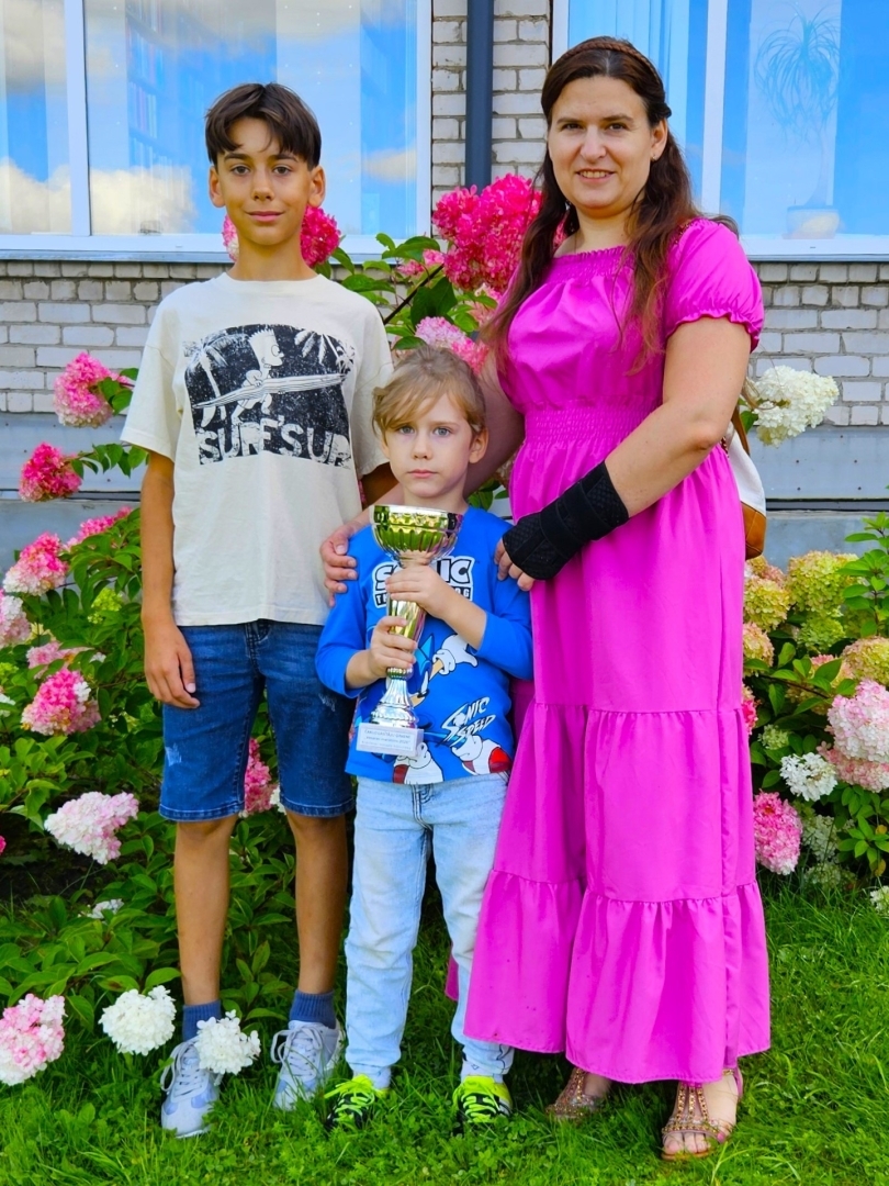 Mamma ar diviem bērniem pie ziediem