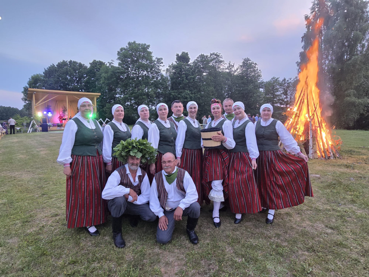 Dalībnieki tautastērpos pozē pie Jāņu ugunskura