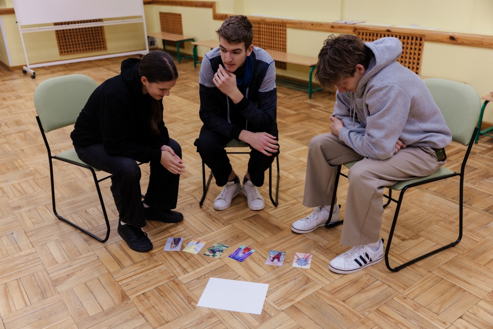 Trīs jaunieši izvēlas kartītes grupas nodarbībā