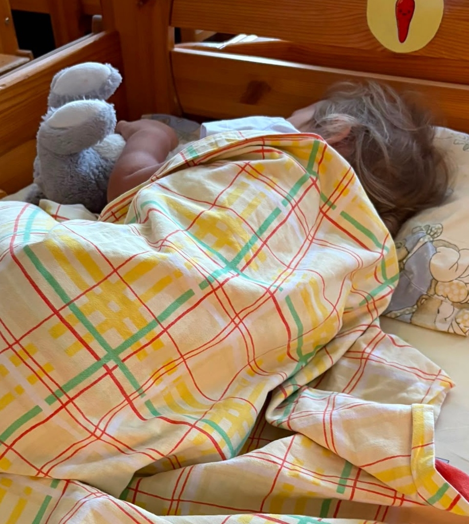 Bērns diendusas laikā guļ bērnudārza gultiņā