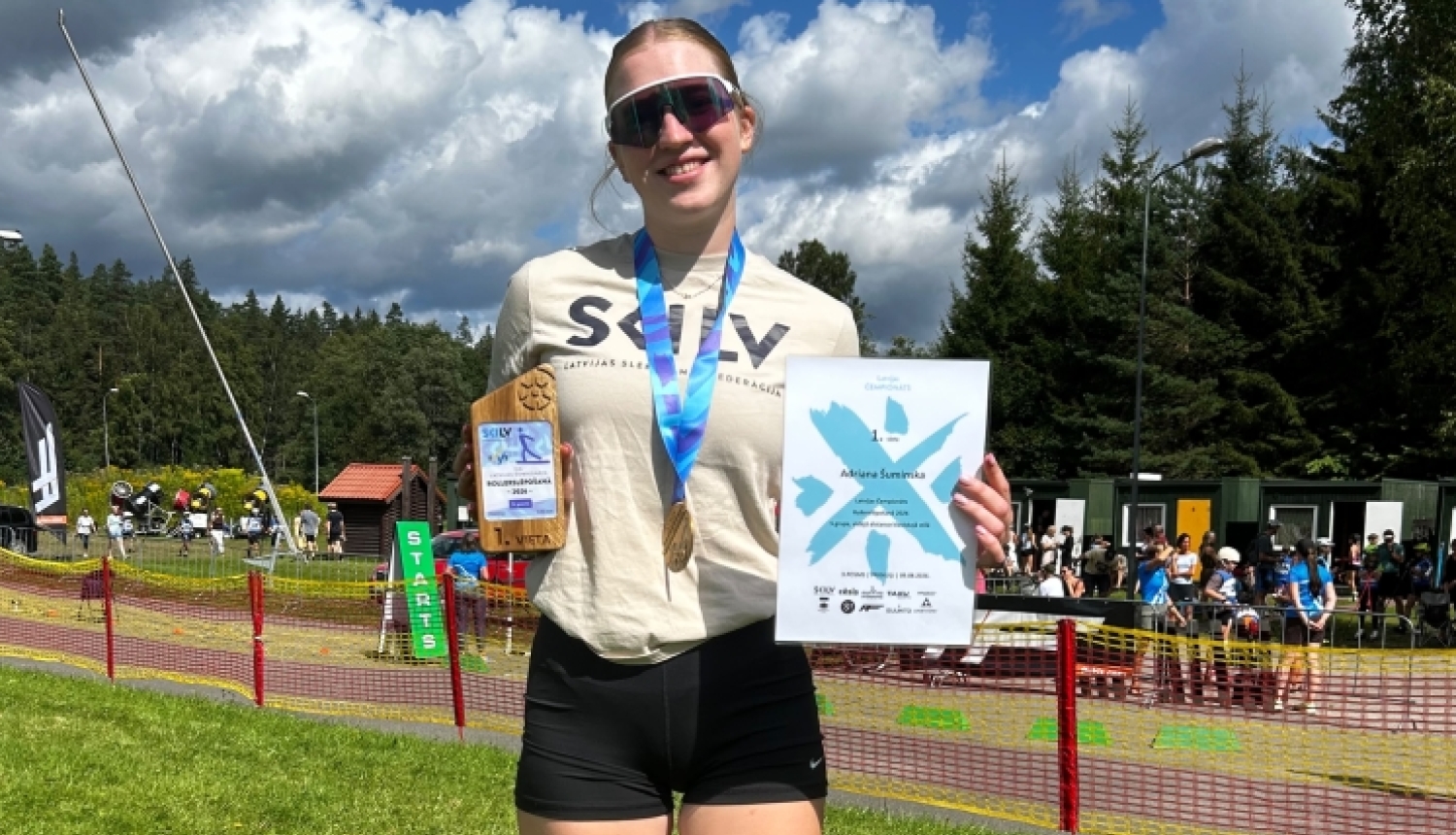 Adriāna ar medaļu, kausu un diplomu