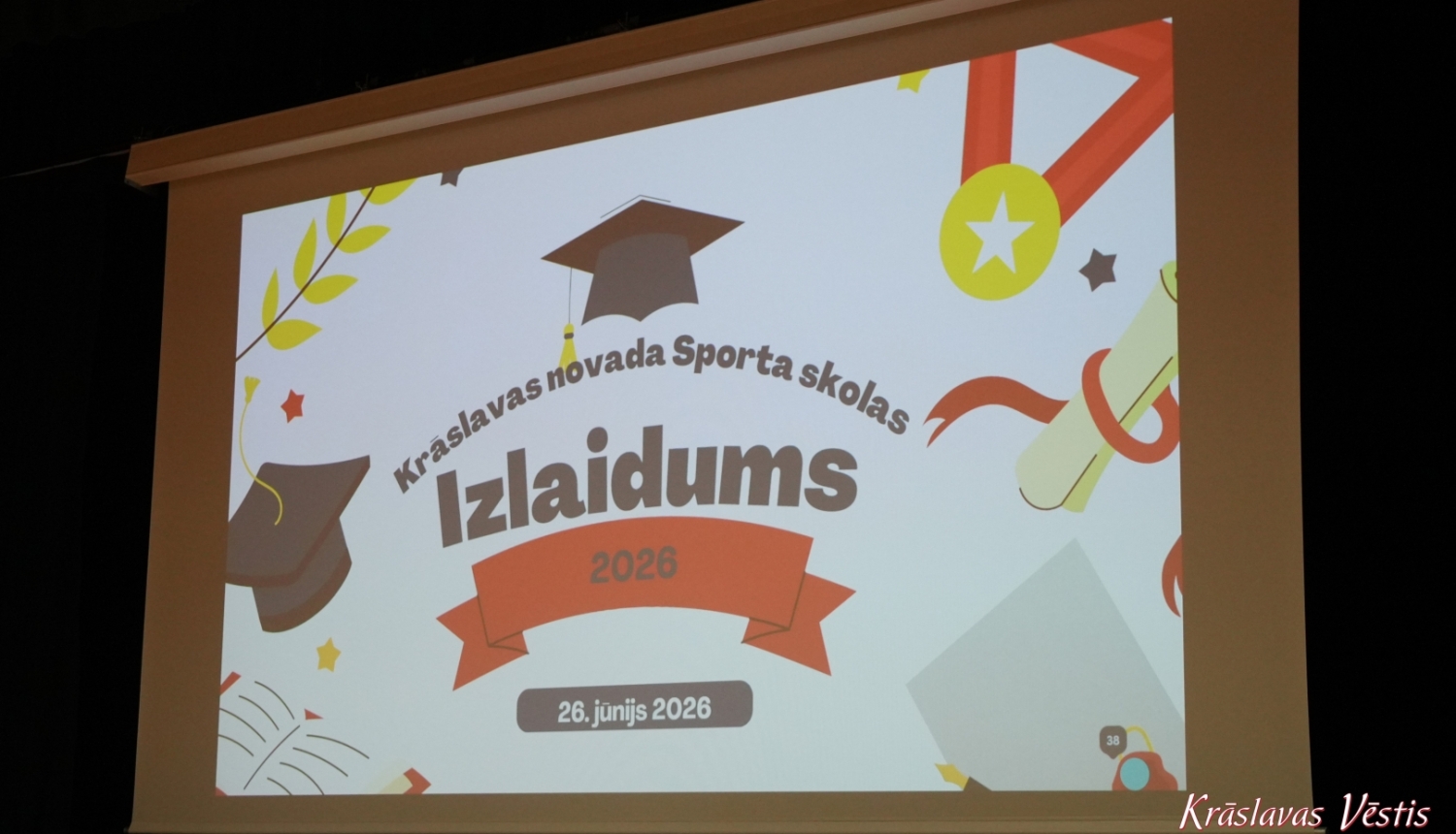Uzraksts uz projektora ekrana “Krāslavas novada Sporta skolas Izlaidums 2026”