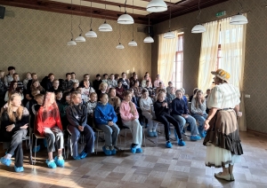 Skolēni klausās gides stāstījumu vēsturiskā telpā