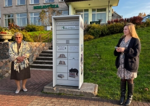 Divas sievietes pie bibliotēkas grāmatu nodošanas skapja