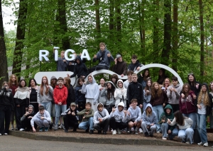 Skolēnu grupa pie Rīgas Zoodārza zīmes