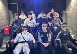 Skolēni sēž 5D kino zālē ar 3D brillēm
