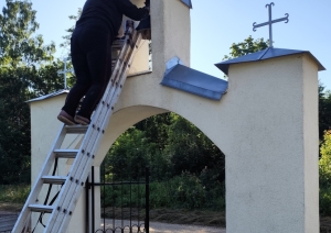 Cilvēks atjauno kapu vārtu zvanu