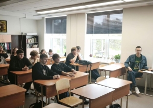 Skolēni klausās prezentāciju klasē.